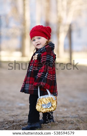 The little blue eyed girl with white hair in red cap and coat holding handbag