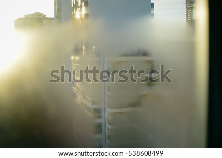 Blurry abstract heart drawn on condensation window glass background. Picture of building silhouette with sun light