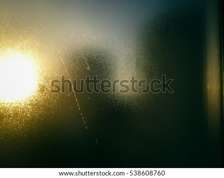 Blurry defocused abstract foggy window water drops background. Picture of building silhouette with sun light