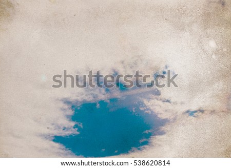 Retro photo with noisy texture. Blue sky with clouds. 
