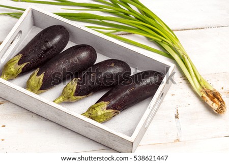 Aubergines in the box and green onions