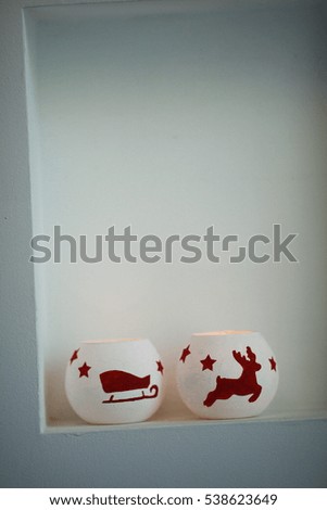 Christmas burning candles with deer and sleds pictured on it on shelf
