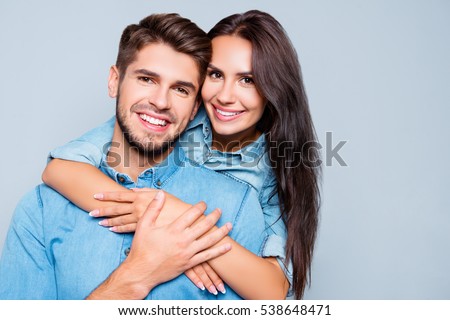 Portrait of happy cute lovers embracing on gray background.