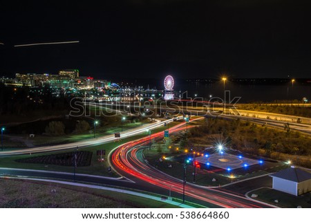 Highway with light streaks and a ferris wheel in the background 