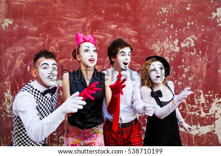 Four mimes looking aside on the background of a red wall. Royalty-Free Stock Photo #538710199