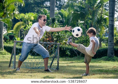Father and son playing in the park at the day time. People having fun outdoors. Concept of friendly family. Picture made on the green meadow.