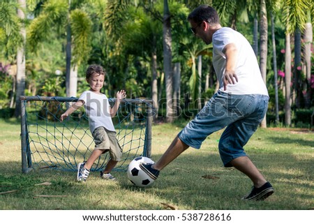 Father and son playing in the park at the day time. People having fun outdoors. Concept of friendly family. Picture made on the green meadow.