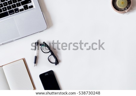 White office desk table with laptop, pen, smartphone, cactus, and notebook. Top view with copy space, flat lay.