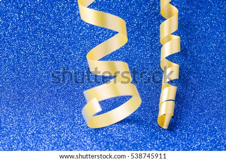 Golden decorative ribbon on blue glitter background. Merry Christmas and Happy New Year card