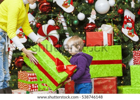 Mom gives a gift to the kid on the background of the Christmas tree