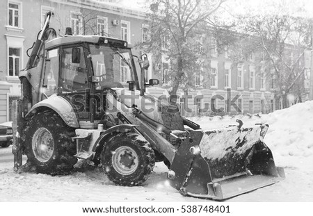 tractor for snow removal is parked on a city street after work