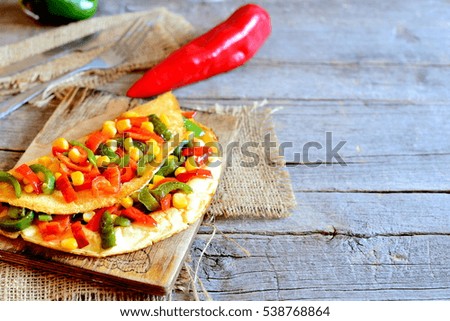 Stuffed omelette on old wooden background with copy space for text. Healthy fried omelette stuffed with red and green bell peppers and canned corn. Vegetarian eggs omelet recipe. Rustic style