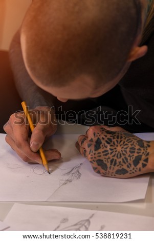 Male tattooer creating tattoo sketch on paper, closeup