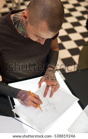 Cropped shot of male tattoo master making sketch for client