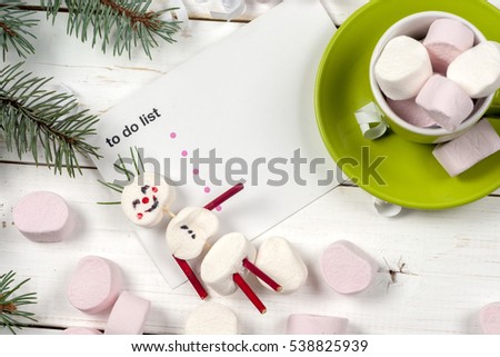 Christmas card with fun marshmallow snowman in green cup, Christmas tree, snow and sled. Copy space for text.