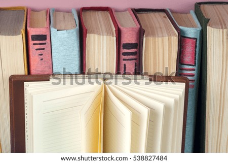 Open book, stack of colorful hardback books on light table. Back to school. Copy space for text. Toned image.