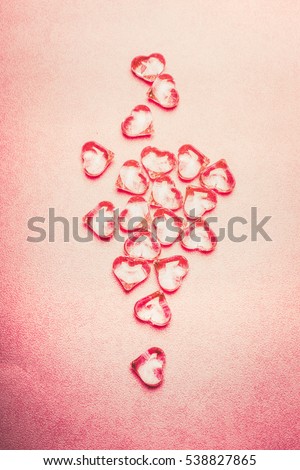 Glass hearts composing on pink background, top view