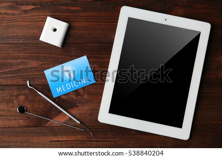 Business card, tablet and dental tools on wooden background. Medical service concept