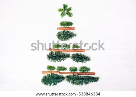 Christmas tree made of fir branches. White wooden rustic background. Winter flat lay style picture.