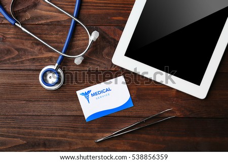 Tablet, stethoscope and card on wooden background