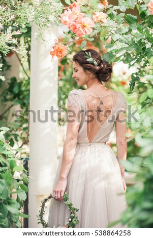 Bride in a beautiful dress with a bouquet of flowers and greener