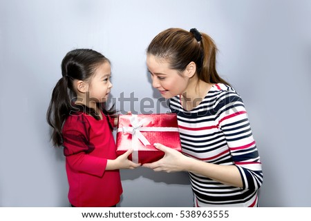 Happy Asian family, Daughter giving gift box to mother on grey background, Mother and daughter with red gift box, christmas day concept.