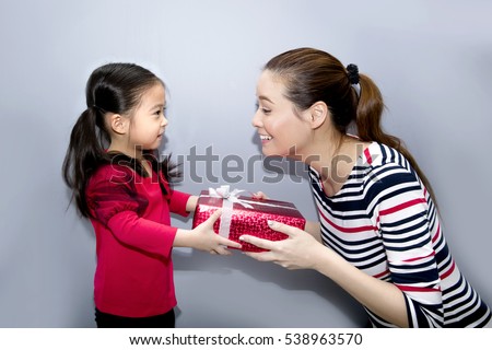 Happy Asian family, Daughter giving gift box to mother on grey background, Mother and daughter with red gift box, christmas day concept.