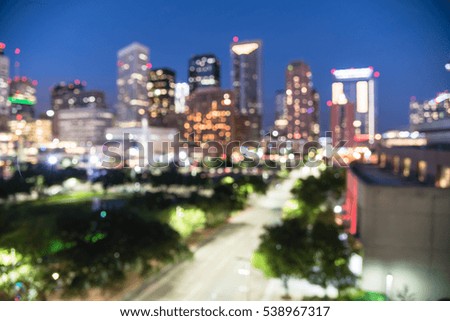Blurred abstract with bokeh light downtown Houston illuminated at blue hour with green city park and modern skylines and traffic light. Its the most populous city in Texas and fourth-most in America.