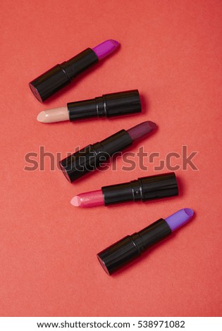 Lipstick cosmetics arranged on a vibrant red background