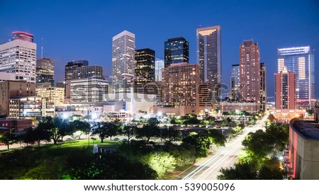 Aerial view downtown Houston illuminated at blue hour with green city park and modern skylines light. The most populous city in Texas, fourth-most in US. Architecture and travel background. Panorama.