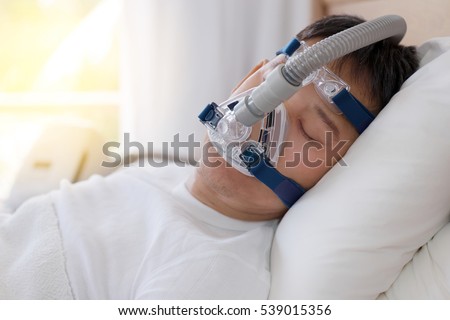  
Healthy senior man wearing cpap mask sleeping smoothly all night on his back without snoring,side view with backlit.Obstructive sleep apnea therapy. Royalty-Free Stock Photo #539015356