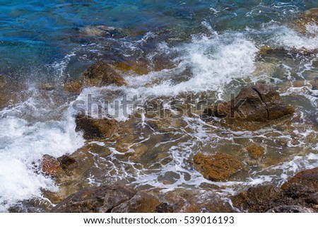Rocky beach. Boulders in seawater. Small waves beating against the shore. Natural beautiful landscape.