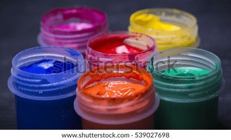 Bright multi-colored paint on black wooden background. for the artist. Education.