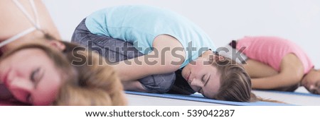 Panoramic picture of relaxed young women resting on exercise mats after training class
