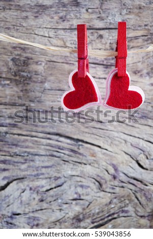 Love Valentine's hearts natural cord and red clips hanging over rustic driftwood texture background