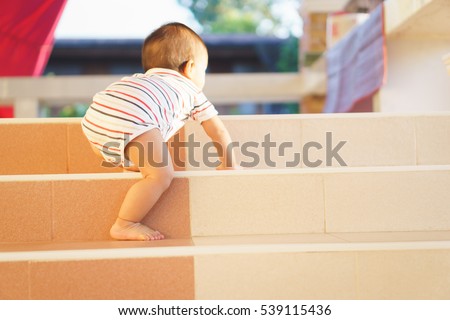10 months adorable Asian baby development , climbing up stairs at home Royalty-Free Stock Photo #539115436