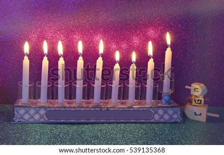 Menorah with glitter light of candles is a traditional symbol for Hanukkah holiday. Low key image toned for vintage style 