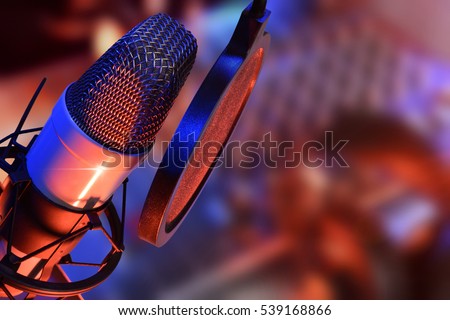 Studio microphone with headphones and mixer background with blue and red lights live production. Elevated view
