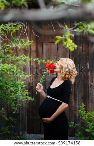 beautiful pregnant woman in black dress standing outdoors