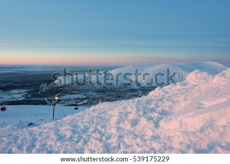 The winter evening landscape with the Russian city and snow mountains. This photo was taken in Kirovsk in Khibiny mountains, Murmansk Region, Russia. 