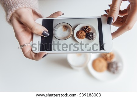 Top view picture of lady sitting in cafe and making photo of food.