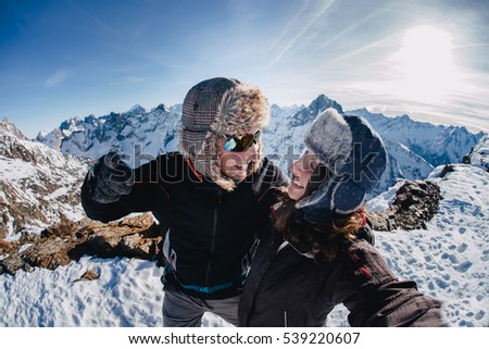 Funny couple taking o selfie on the top of the mountain in winter