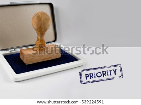 Wooden stamp on a desk PRIORITY