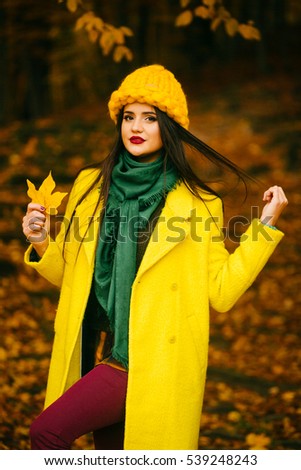 Happy young woman in park on sunny autumn day.