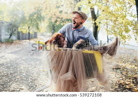 young man rolls his woman in a basket for shopping