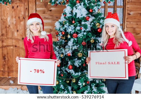 Laugh nice girls holding  -50% fifty and final sale banners. Christmas and New year are coming. Discounts everywhere.