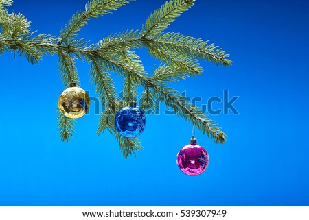 Over blue background Christmas-tree branch decorated with New Year's toys