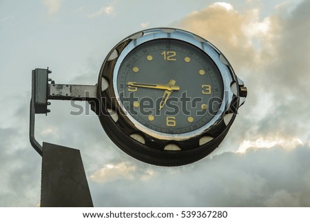 big round street clock with sunset clouds and blue sky background