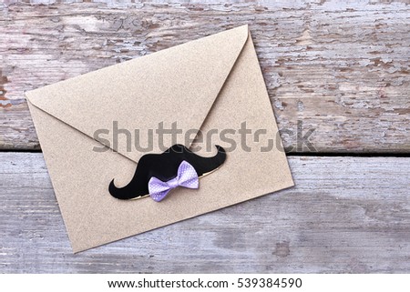 Bow tie on envelope. Props mustache near bow tie. Stylish party invitation.