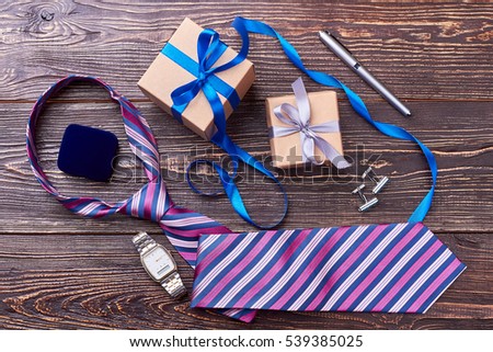 Gift boxes and wrist clock. Tie near cufflinks and pen. Create an elegant look.